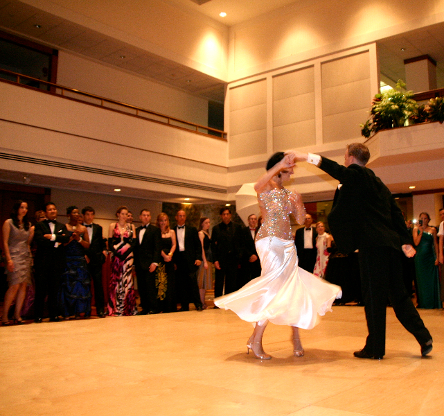 man and woman dancing on ballroom floor surrounded by well dressed people